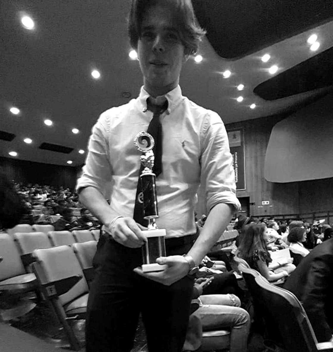 Holding a trophy in a full auditorium